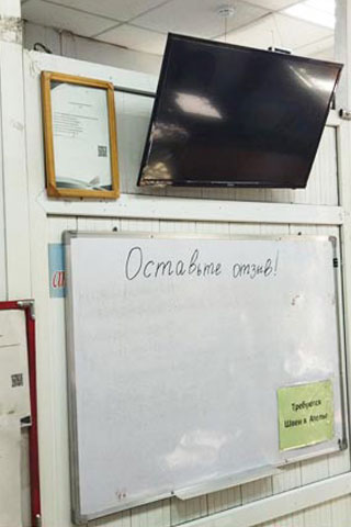 Выключенный экран в ателье рядом с маркерной доской